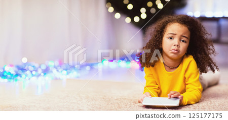 I wanted doll. Sad african little girl with unwanted Christmas gift cellphone, free space 125177175
