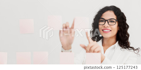 Business Plan. Smiling mexican businesswoman sharing her ideas on sticky notes over glass wall at office Business Plan. Smiling mexican businesswoman sharing her ideas on sticky notes over glass wall at office 125177243