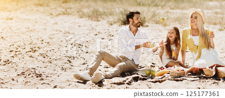 Family resting in nature, having picnic on blanket. Parents spending time with daughter 125177361