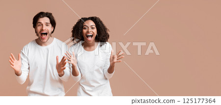 Shocked Multiracial Couple Exclaiming With Amazement And Emotionally Gesturing With Hands Over Yellow Background With Empty Space 125177364