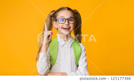 Idea Concept. Excited Primary School Girl Pointing Finger Up Over Yellow Studio Background. Empty Space Idea Concept. Excited Primary School Girl Pointing Finger Up Over Yellow Studio Background. Empty Space 125177366