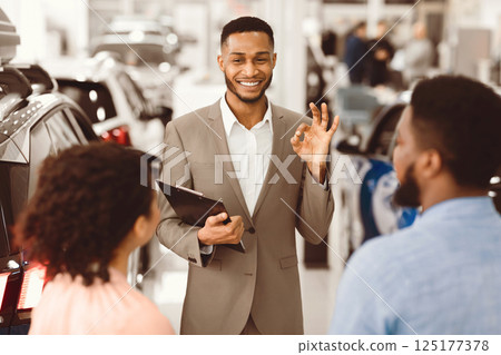 Professional Car Dealer Gesturing Okay Talking With Clients Offering Great Deal Working In Auto Dealership Store. Selling Automobile. Selective Focus Professional Car Dealer Gesturing Okay Talking With Clients Offering Great Deal Working In Auto Dealership Store. Selling Automobile. Selective Focus 125177378