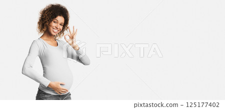 Successful pregnancy. Happy afro woman gesturing okay over white studio background 125177402