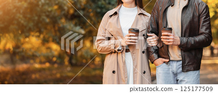Cropped of man and woman drinking coffee while walking by autumn forest, panorama with free space 125177509