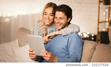 Happy spouses ordering Christmas gifts on tablet, spending winter evening together, free space 125177528