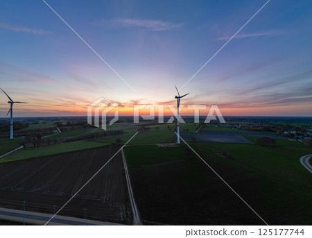 A beautiful scenic landscape featuring wind turbines set against a breathtaking sunset 125177744
