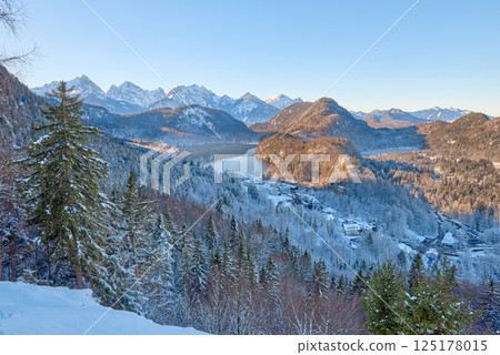 Beautiful winter morning landscape with snowy mountains and a serene lake, icy landscape surrounding majestic peaks, dawn light in January 125178015