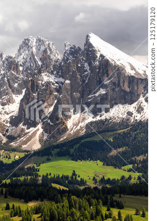Majestic mountain peaks with verdant forests and snow-capped summits in scenic landscape near Valley of Funes at Dolomites, Italy Majestic mountain peaks with verdant forests and snow-capped summits in scenic landscape near Valley of Funes at Dolomites, Italy 125179120