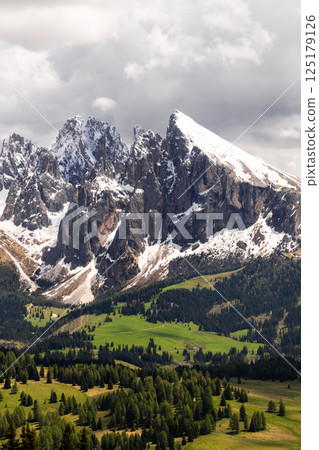 Majestic mountain range with snow-covered peaks under dramatic sky near Valley of Funes at Dolomites, Italy 125179126
