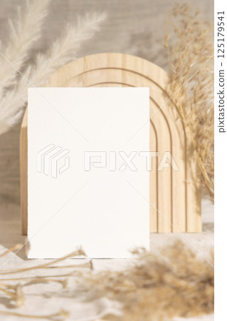 Blank card near dry pampas grass and beige wooden decor on linen closeup, minimal mockup 125179541