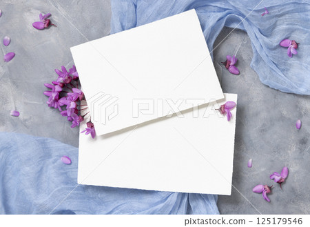 Blank cards on fabric near wild purple flowers top view on gray, spring wedding mockup 125179546