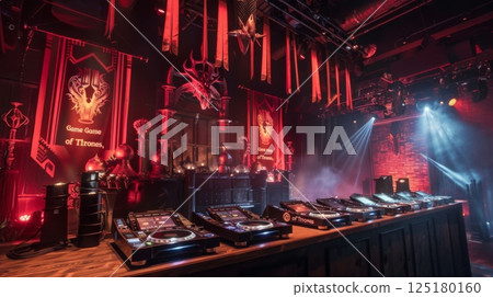 In a dimly lit room with red and black decor, a DJ booth stands with Game of Thrones banner and red drapes. Multiple turntables and speakers are on the wooden counter 125180160