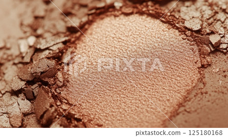 A close-up shows the bronzer's fine texture and rich color, intertwined with crushed fragments, making it ideal for enhancing natural beauty in makeup. 125180168