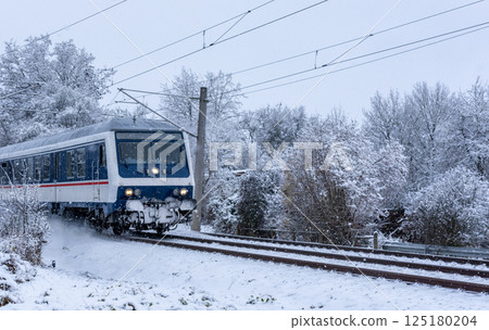 Passenger train traveling through snow, in nature, in Germany Passenger train traveling through snow, in nature, in Germany 125180204