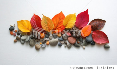 Vibrant autumn leaves in various colors are creatively arranged alongside smooth pebbles on a light background. 125181364