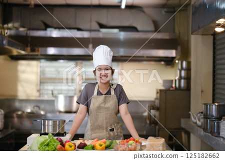Portrait young teen girl cook student. Cooking class. Culinary classroom. Happy young woman students for cooking in cooking school. 125182662