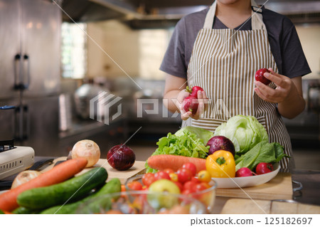 Culinary student standing confidently in training kitchen with fresh ingredients ready for cooking practice 125182697