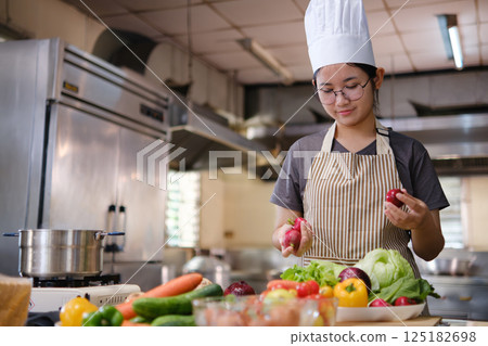Culinary student standing confidently in training kitchen with fresh ingredients ready for cooking practice 125182698