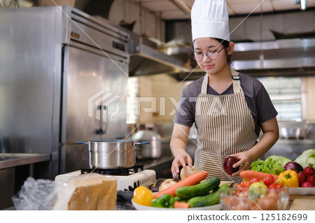 Culinary student standing confidently in training kitchen with fresh ingredients ready for cooking practice Culinary student standing confidently in training kitchen with fresh ingredients ready for cooking practice 125182699