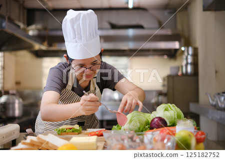 Focused chef carefully a gourmet sandwich in a professional kitchen with fresh ingredients in view Focused chef carefully a gourmet sandwich in a professional kitchen with fresh ingredients in view 125182752