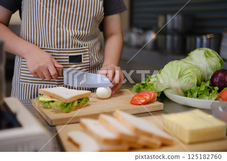 Focused chef carefully a gourmet sandwich in a professional kitchen with fresh ingredients in view 125182760