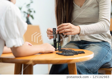 Family Playtime and Creativity. A mother helping her daughter build a domino structure during an engaging game. 125182983