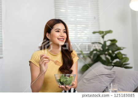 Healthy Eating and Positive Mindset. A smiling woman enjoys her nutritious meal, embracing a positive start to the day. 125183085