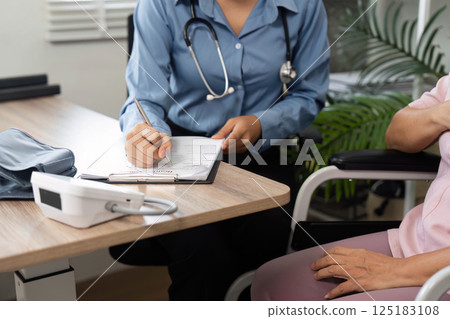 Consultation and Health Check. A healthcare professional documents patient information during a check-up. Consultation and Health Check. A healthcare professional documents patient information during a check-up. 125183108