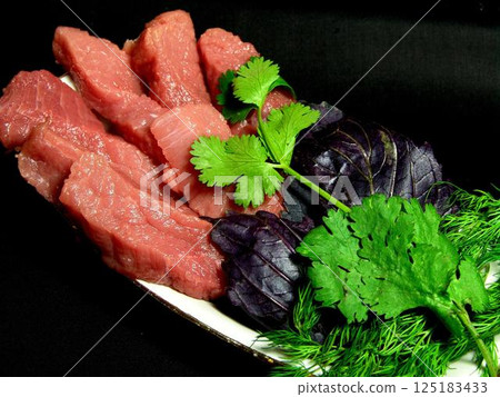Raw uncooked meat with greens on a plate close view background 125183433