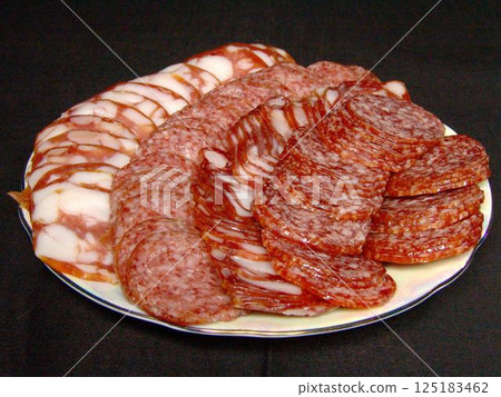 Slices of sausage and lard on a plate over solid background Slices of sausage and lard on a plate over solid background 125183462