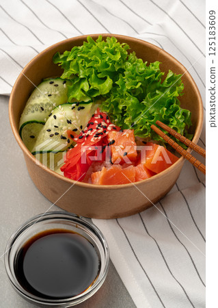 Fresh sushi bowl with salmon, avocado, and greens served with soy sauce 125183609