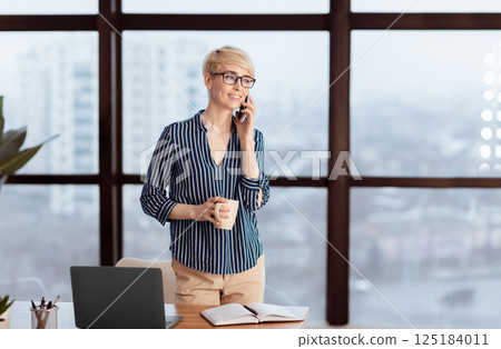 Successful Businesswoman Talking On Mobile Phone Standing Near Window In Modern Office. Business Communication. Selective Focus, Free Space 125184011