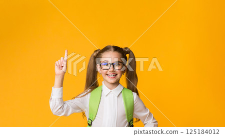 Positive nerdy schoolgirl pointing finger up having idea or question over yellow background. Copy space Positive nerdy schoolgirl pointing finger up having idea or question over yellow background. Copy space 125184012