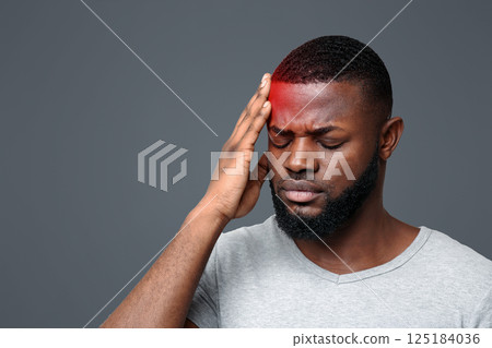 Young black man suffering from headache, touching highlighted forehead 125184036