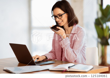 Technology And Communication. Happy businesswoman in glasses using voice command recorder on mobile phone, copyspace Technology And Communication. Happy businesswoman in glasses using voice command recorder on mobile phone, copyspace 125184061