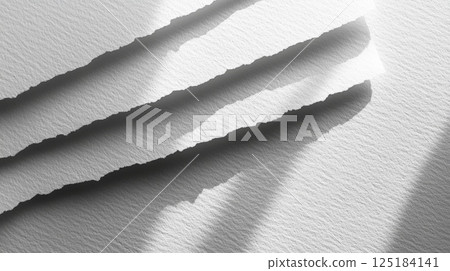 Torn edges of white paper create a textured effect, with soft shadows enhancing the details, illuminated by gentle morning light in a calm environment. 125184141