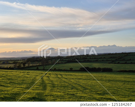 Cloudy Sky Over Agricultural Highland Landscape with Mountains 125184267