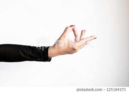 Female hand in gesture with black sleeve and red nails against white background 125184371