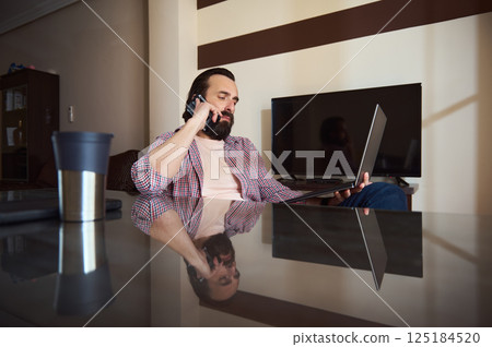 Young Professional Working Remotely at Home Using Laptop and Smartphone 125184520