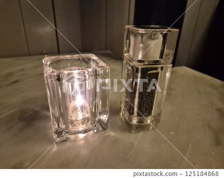 Candle and pepper on a restaurant table background 125184868