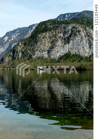 Stunning mountain landscape with lake reflection. Alpine lakeside house at foot of rocky mountain. Tranquil scene with forestcovered hills and clear water. Stunning mountain landscape with lake reflection. Alpine lakeside house at foot of rocky mountain. Tranquil scene with forestcovered hills and clear water. 125185449