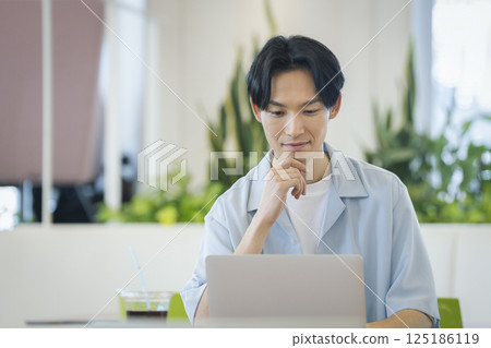 一名 30 多歲的男子正在使用筆記型電腦 125186119