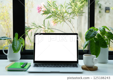 Laptop with white screen and coffee drink, cozy indoor work space Laptop with white screen and coffee drink, cozy indoor work space 125186243