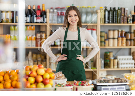 Girl stands near counter in grocery department of store, gesturing to look at assortment 125186269
