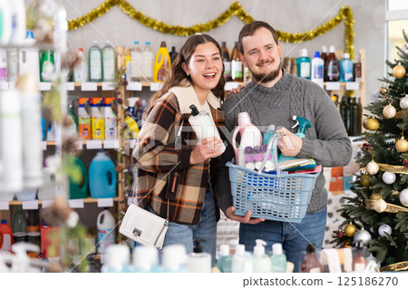 Cheerful couple shopping for home care products in Christmas decorated store 125186270