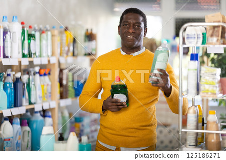 Male shopper selects dishwashing sponges in the household goods section of supermarket 125186271