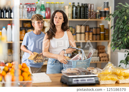 Adolescence boy with mother choose consider snacks in shop Adolescence boy with mother choose consider snacks in shop 125186370