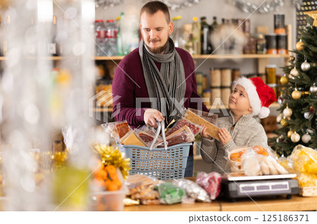 Young man with son choosing sweets at grocery store 125186371