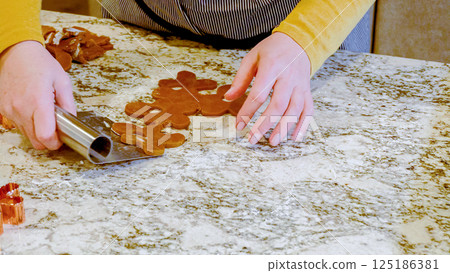 Using various festive cookie cutters, we're cutting out charming gingerbread cookies from the rolled dough on the sleek marble counter, bringing holiday cheer to the modern kitchen. 125186381