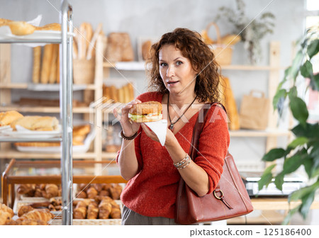 Positive woman with burger in bakehouse Positive woman with burger in bakehouse 125186400